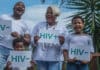 En man en kvinna och barn som håller upp ett papper med texten HIV