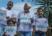 En man en kvinna och barn som håller upp ett papper med texten HIV