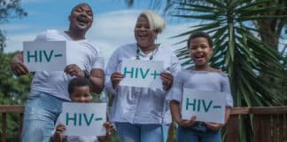 En man en kvinna och barn som håller upp ett papper med texten HIV