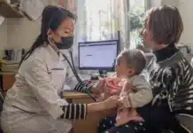 En läkare och en baby som sitter i famnen på en kvinna