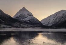 Snötäckta berg med vatten i förgrunden