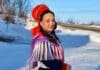 En kvinna i traditionell samisk dräkt i vintermiljö.